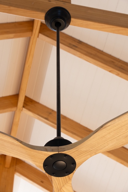 Timber ceiling fan hanging from a downrod on a vaulted covered patio